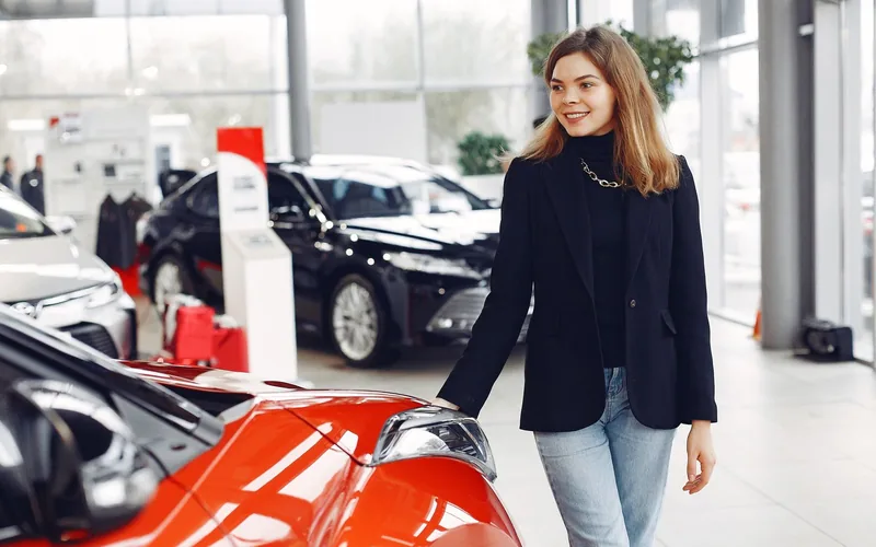 Bezoeker loopt langs de auto in de showroom van een autobedrijf
